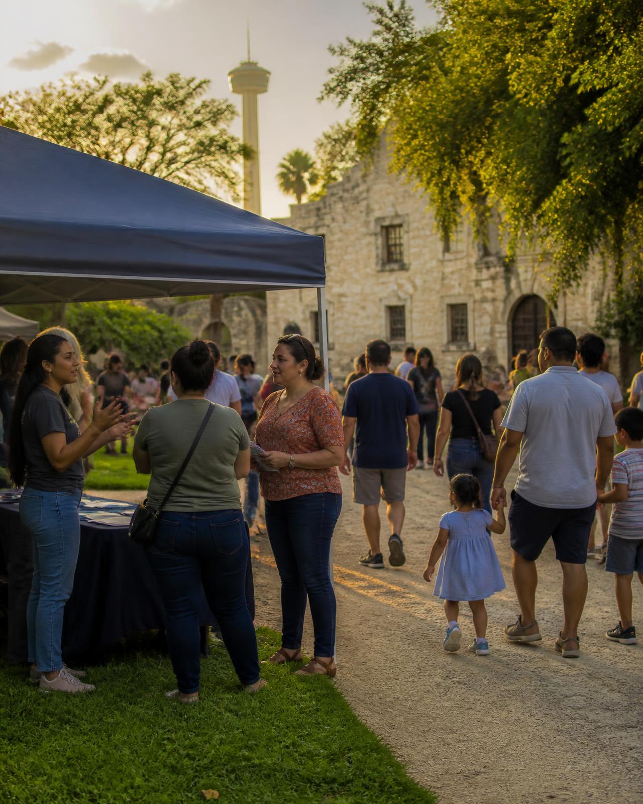 An outdoor community event where a representative talks with attendees under a canopy tent